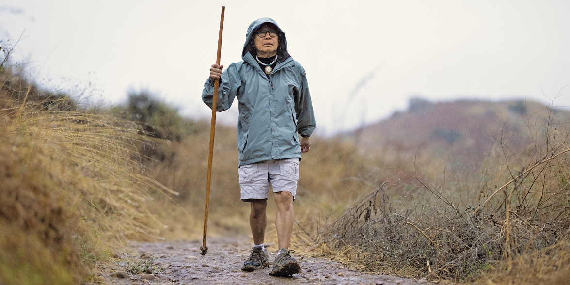 Bruce Kanegai hikes on a rainy mountain trail.