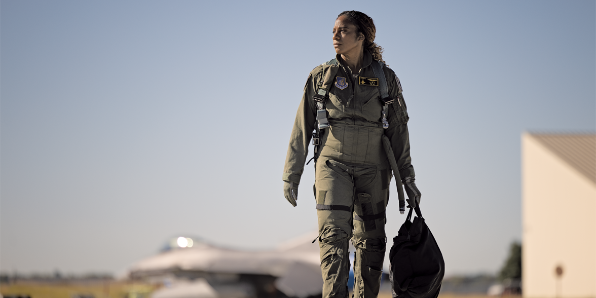 Rochelle Kimbrell caminando por una pista con un avión de combate en el fondo.